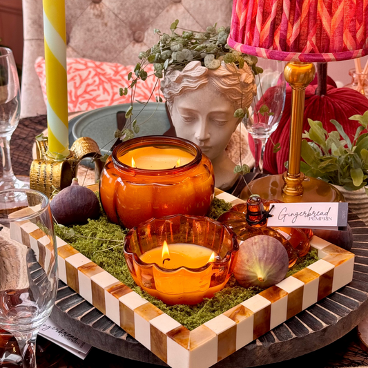 Decorative table setting with candles, fruits, and a lamp in a warm indoor autumnal  setting.