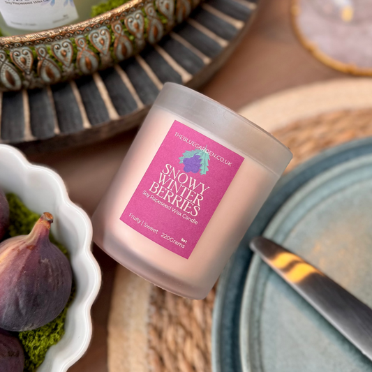 Winter soy candle with a pink label on a table setting with figs and cutlery