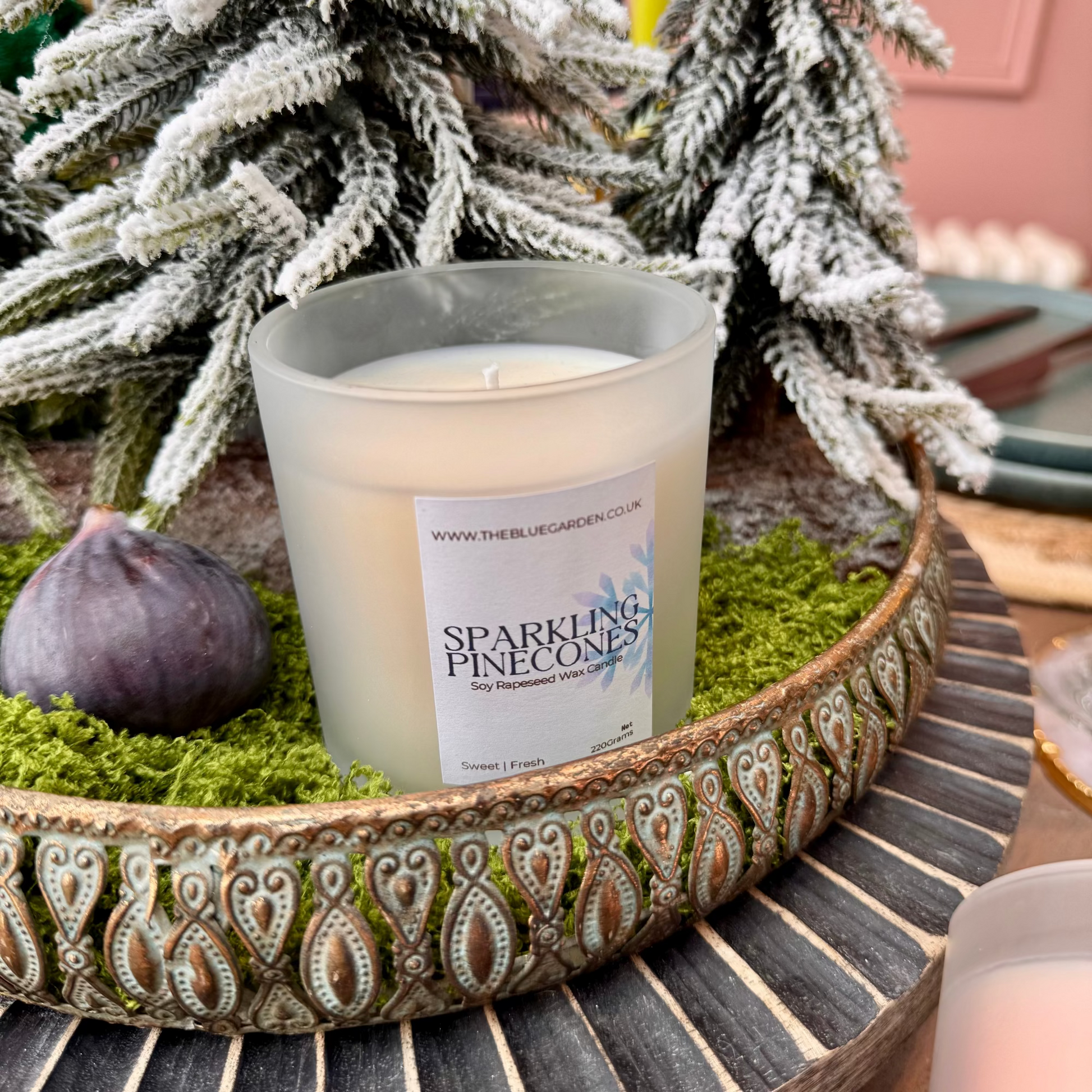 Scented soy Christmas pinecone candle on mossy table tray with fifgs
