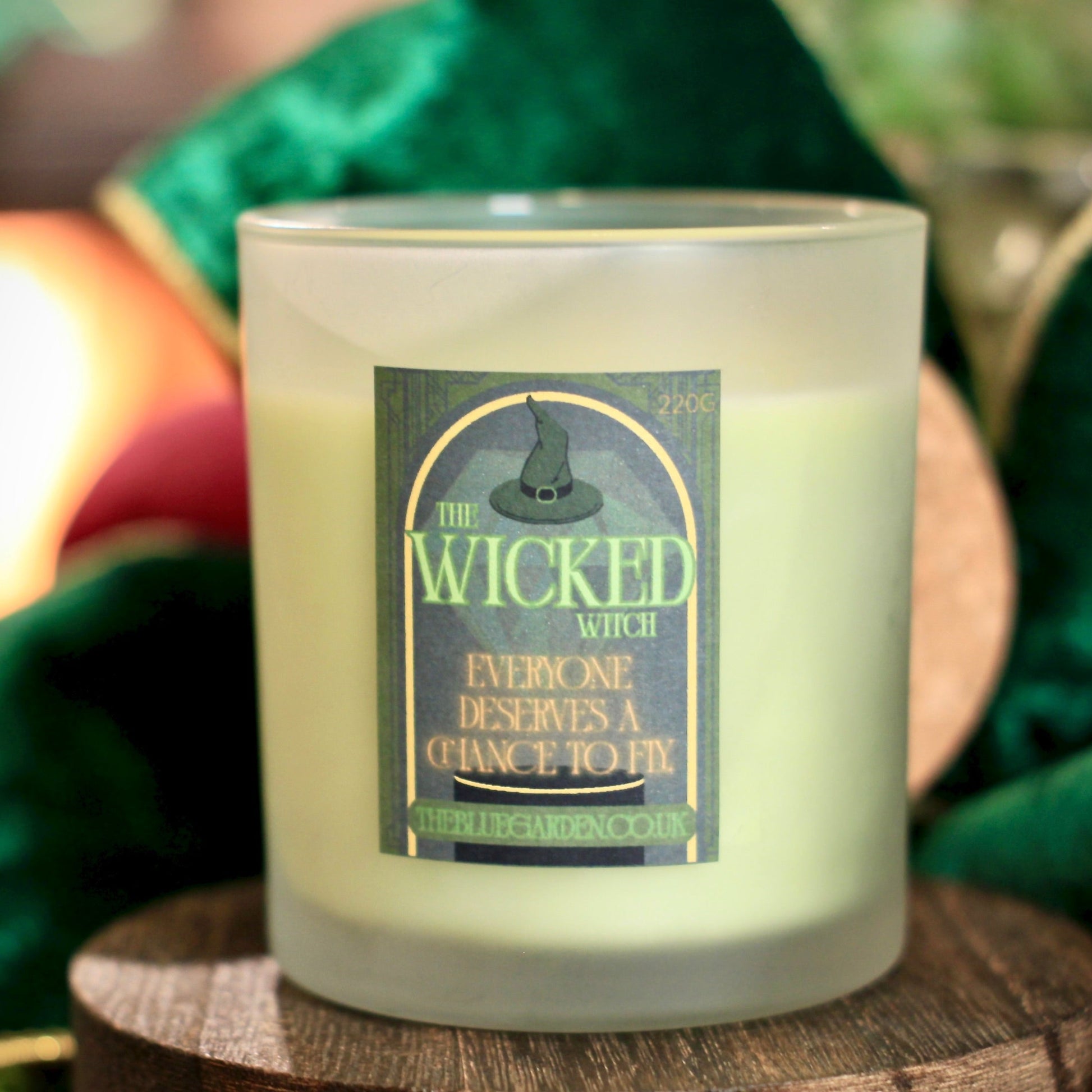 Candle with a label on a wooden surface with greenery in the background