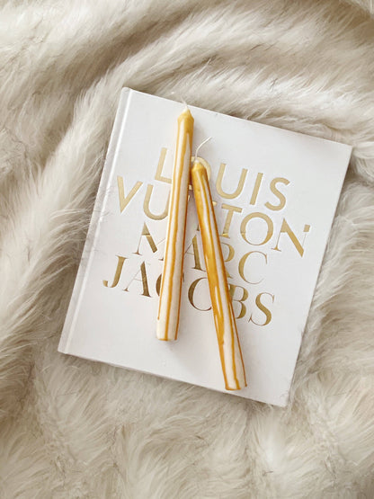 Two gold candles on a Louis Vuitton magazine on a fur surface