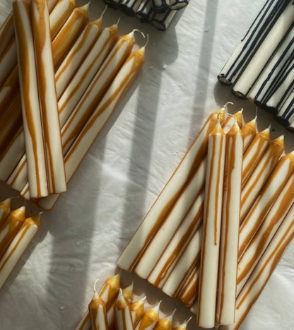 Striped candles on a white surface with shadows cast by the candles.
